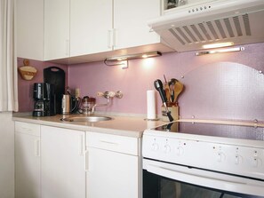 A kitchen with white cabinets, a stainless steel sink, a coffee maker, and a stove. - 6 Person Holiday Home in Hasle (Hasle)