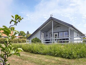 A single-story building with a gabled roof, a porch with a railing, and a clear sky. - 6 Person Holiday Home in Hasle (Hasle)