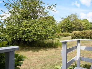 Eine Holzterrasse mit Blick auf eine Wiese und Bäume.