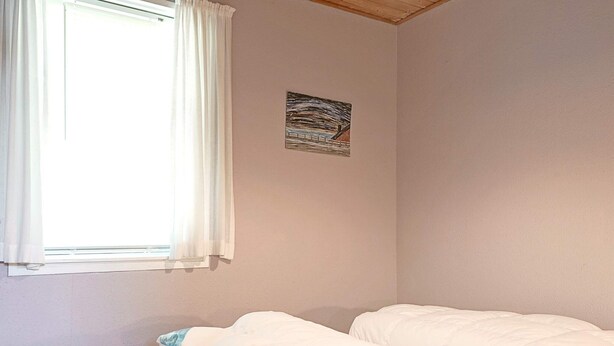 A bedroom with a single bed, a window with curtains, and a wall-mounted picture. - 6 Person Holiday Home in Hasle (Hasle)