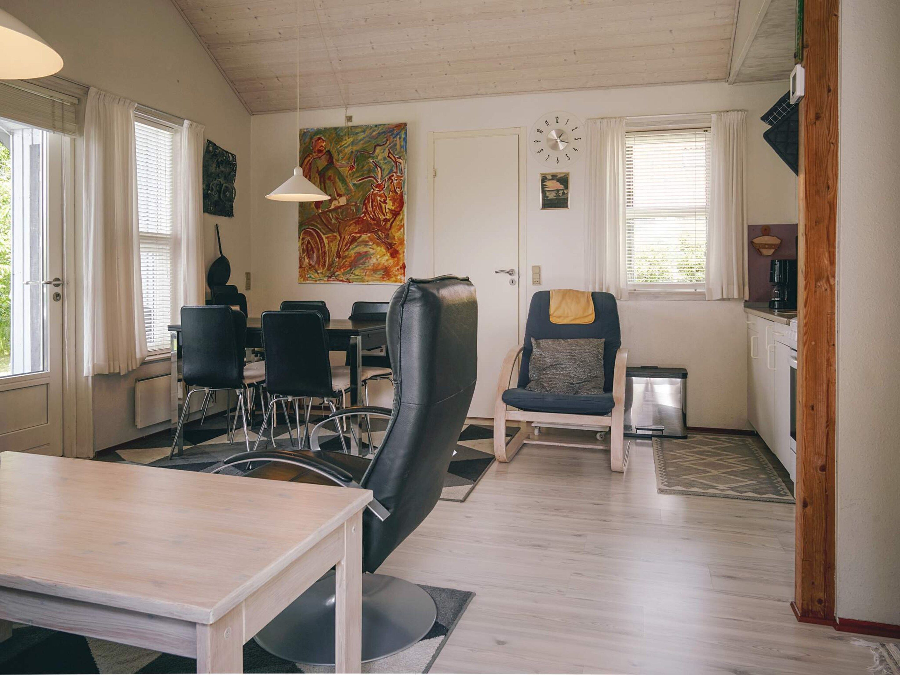 Un coin repas comprenant une table, des chaises, un tableau et une horloge au mur.