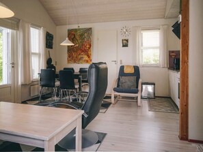 A dining area with a table, chairs, a painting, and a clock on the wall. - 6 Person Holiday Home in Hasle (Hasle)