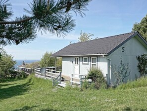 A small white building with a grey roof, number 5, surrounded by grass and trees.