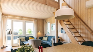 A cozy living room with a sofa, a dining table with candles, and a staircase. - 8 Person Holiday Home in Faaborg-by Traum (Faaborg)