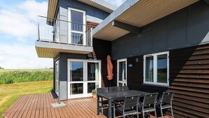 A modern two-story house with a deck, outdoor seating, and a large window. - 8 Person Holiday Home in Faaborg-by Traum (Faaborg)