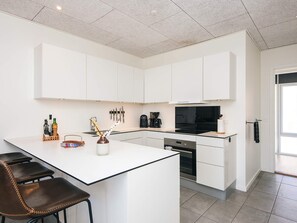 A modern kitchen with white cabinetry, a central island with bar stools, and a black stove.