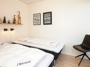 A bedroom with two beds, a chair, and motivational posters on the wall. - 5 Star Holiday Home in Ringkobing (Ringkobing)