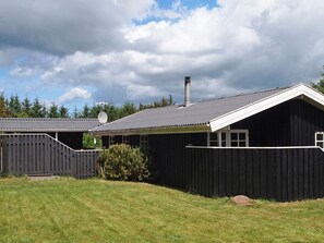 A black wooden building with a sloped roof, a chimney, and a satellite dish. - 4 Star Holiday Home in Blokhus (Blokhus)