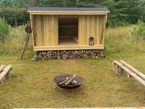 A wooden cabin with a porch, a fire pit, and a lantern. - 4 Star Holiday Home in Blokhus (Blokhus)