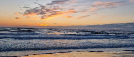 A beach with waves and a sunset.