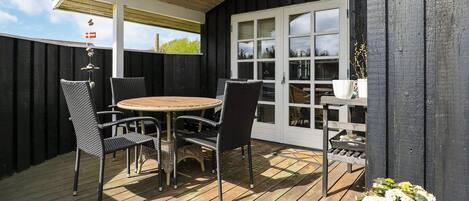 Eine Terrasse im Freien mit einem runden Tisch und Stühlen, einem Holzboden und einem Blumentopf.