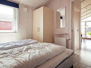 A bedroom with a bed, a wardrobe, a mirror, and a window. - Holiday Home in GrÃ¶mmitz (Groemitz)