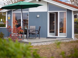 A small house with a patio, a table with chairs, and an umbrella. - Holiday Home in GrÃ¶mmitz (Groemitz)