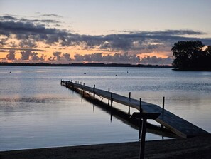 A calm waterfront with a wooden pier extending into the water.