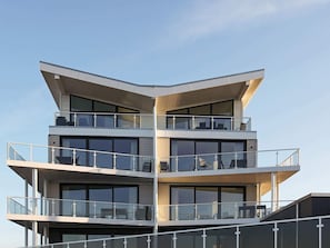 Ein modernes mehrgeschossiges Gebäude mit Balkonen und großen Fenstern.