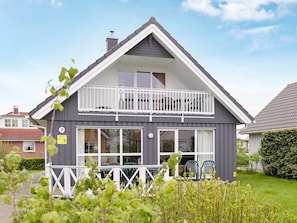 A two-story house with a balcony, large windows, and a fenced front yard. - Holiday Home in Gelting (Gelting)