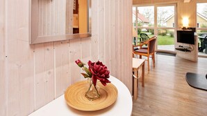 A room with a wooden interior, a dining area with chairs and a table, and a television mounted on the wall.