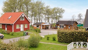 A red building with a sloped roof, a wooden structure with a roof, and a white fence.