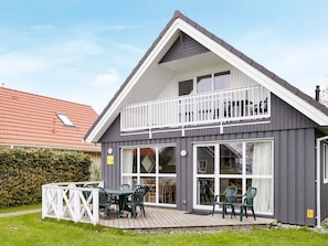 A two-story house with a balcony, large windows, and a deck with outdoor furniture. - Holiday Home in Gelting (Gelting)