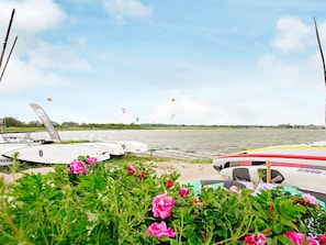 A lakeside view with boats and kitesurfing activity. - Holiday Home in Gelting (Gelting)