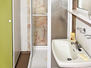 Une salle de bain avec un lavabo blanc, un flacon de lotion et un miroir au-dessus du lavabo.