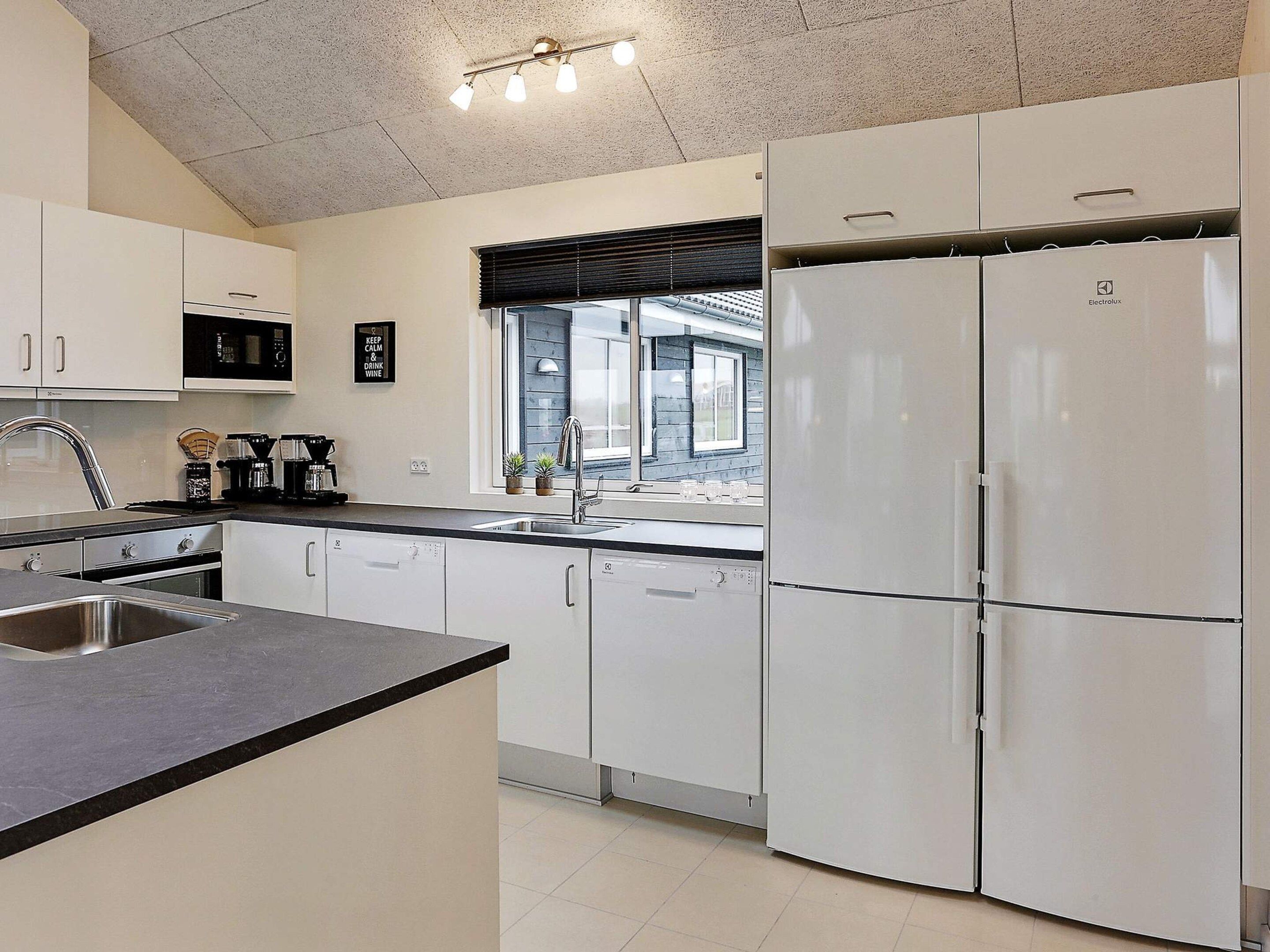 A modern kitchen with white cabinetry, a stainless steel sink, and a built-in oven.