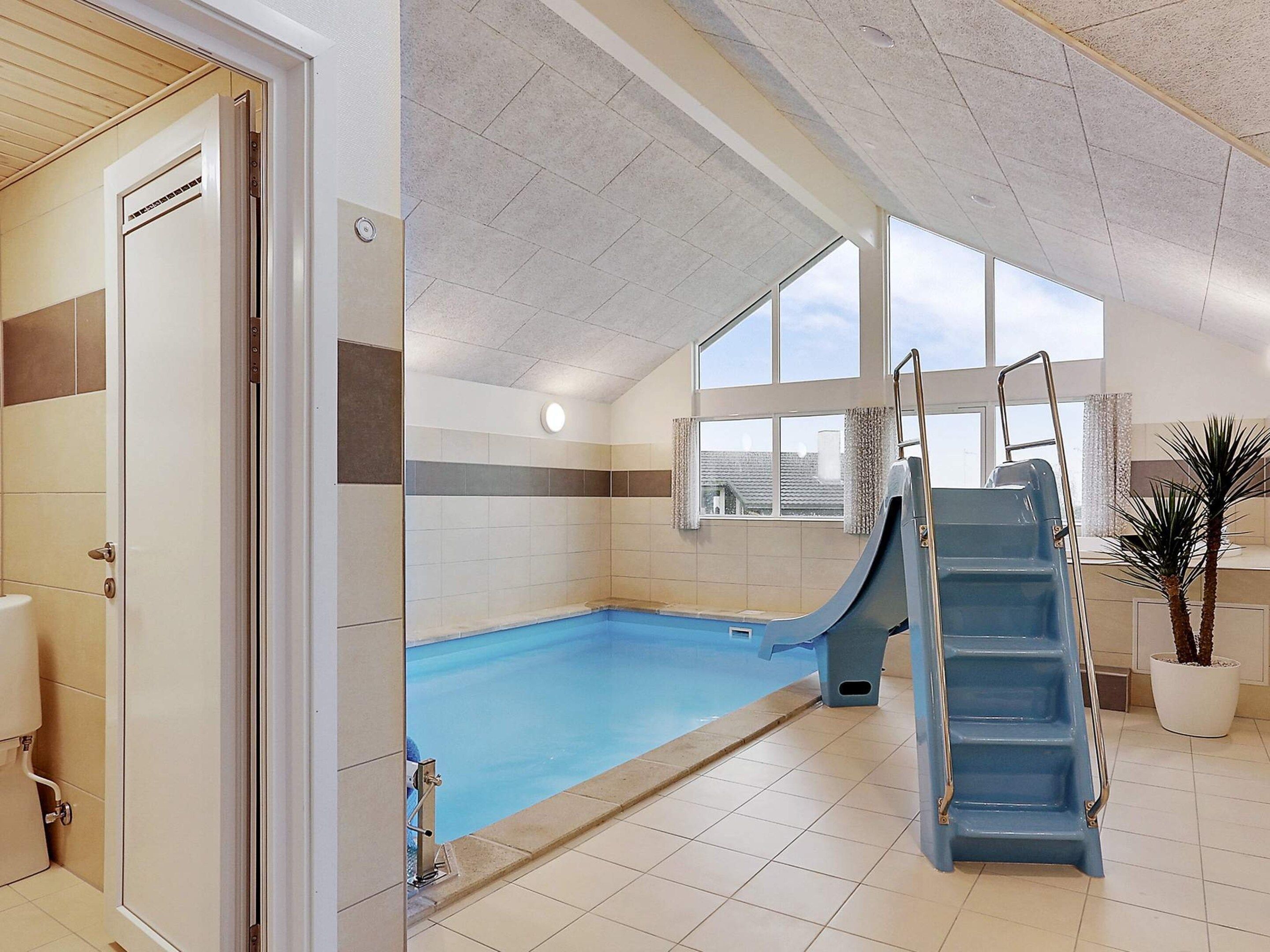 An indoor swimming pool with a slide, a window, and a staircase.