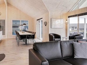 A modern interior with a dining area, a leather sofa, and large windows.