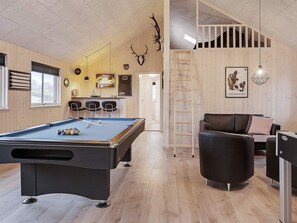 A pool table in a room with wooden walls and a loft area.