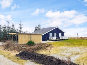 Un bâtiment à deux étages, à l’extérieur sombre, doté d’un porche couvert et d’une zone délimitée par une clôture.