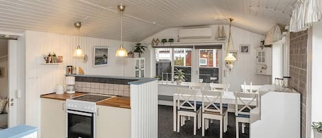 Une cuisine dotée d’un îlot central, de meubles blancs et d’un coin repas avec des chaises blanches.