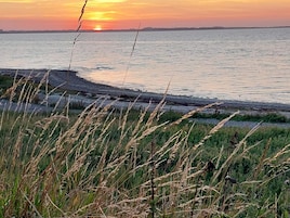 A sunset over a calm body of water with grassy foreground.