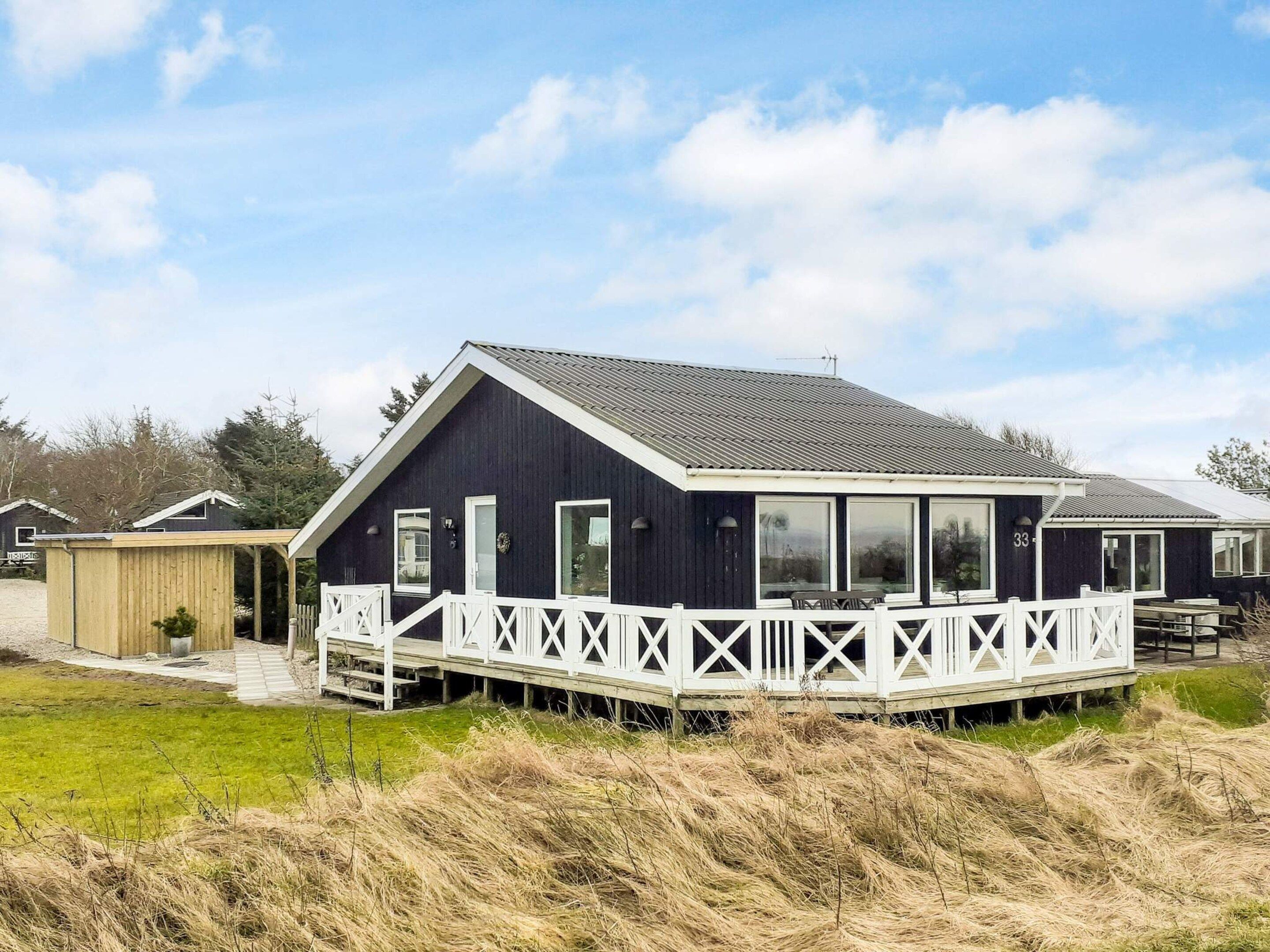 A dark-colored house with a white porch and a covered outdoor seating area.