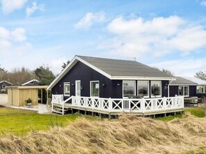 Et mørkt hus med veranda og overdækket siddeområde.