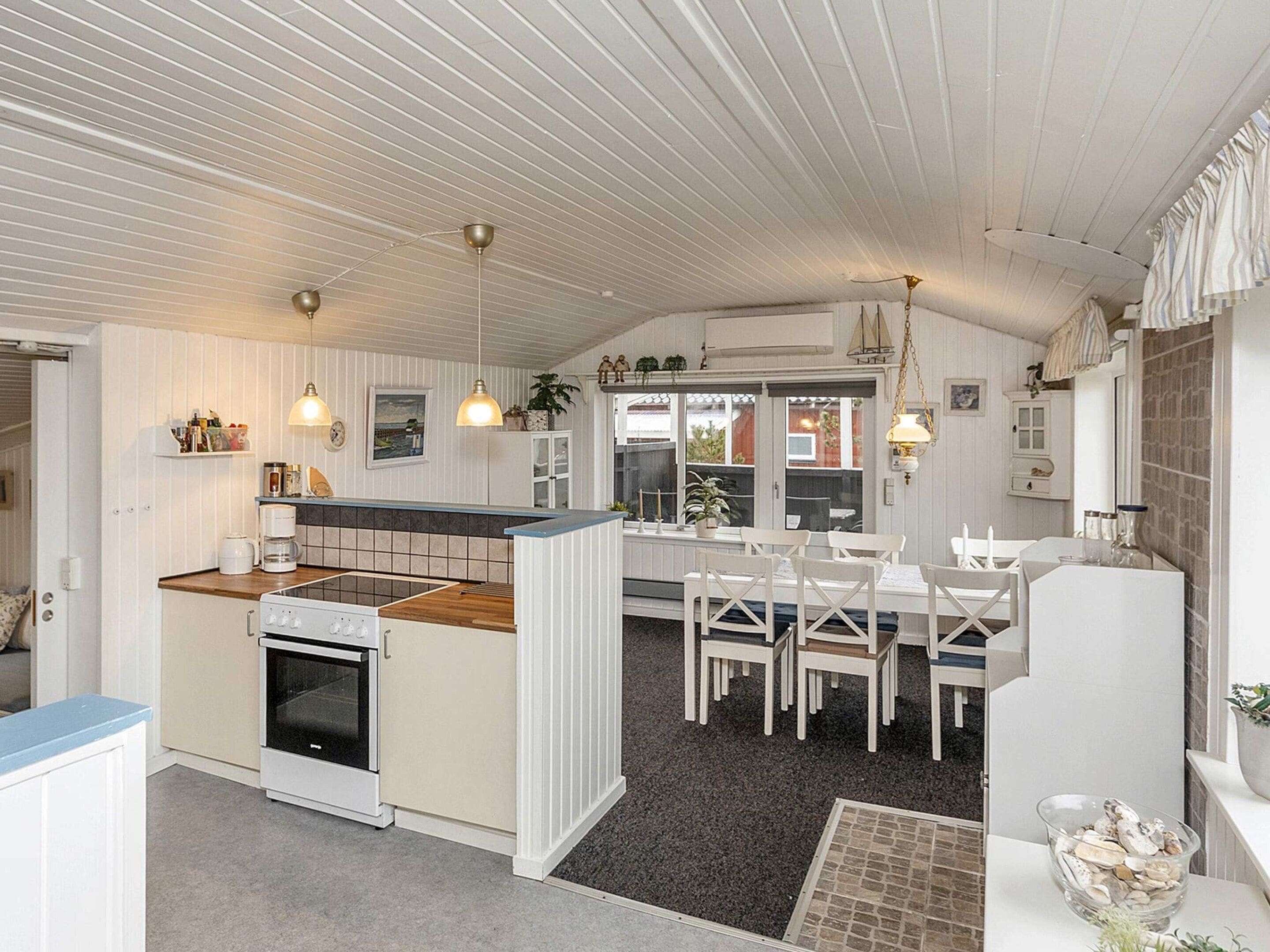 Keittiössä on sisäänrakennettu uuni, valkoisilla tuoleilla varustettu ruokailutila sekä pieni keittiösaareke, jossa on pesuallas.
