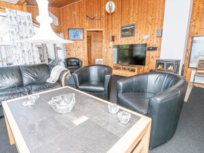 A cozy room with a leather sofa, two armchairs, a coffee table, a TV, and a fireplace.