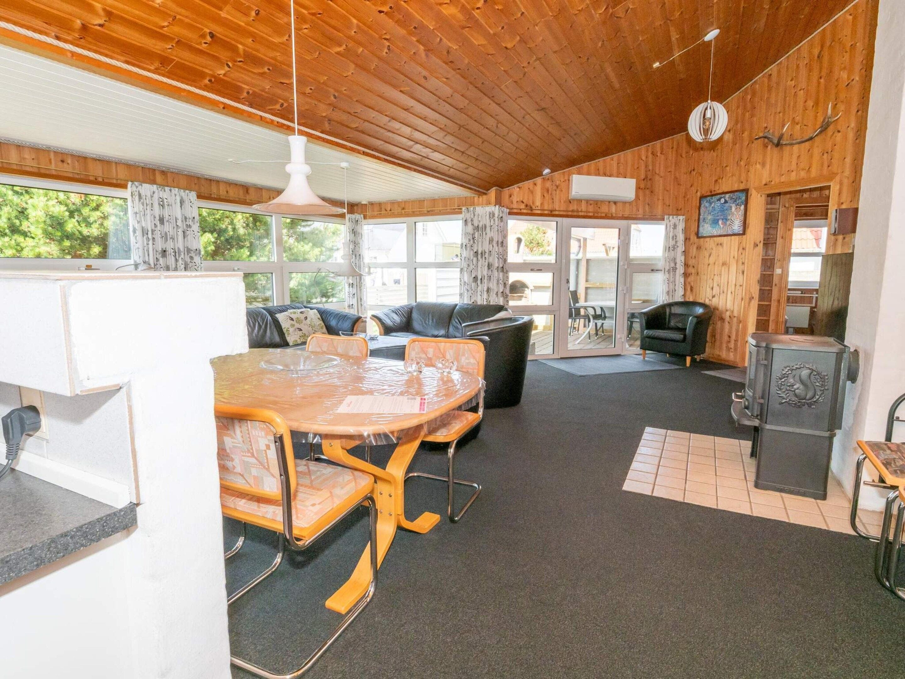 A cozy cabin interior with a dining area, seating, and a wood stove.