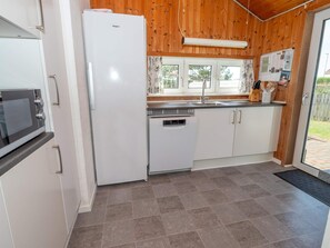 A kitchen with a refrigerator, dishwasher, and a microwave. - 4 Star Holiday Home in Thisted (Thisted)
