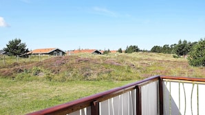 A wooden deck with a white railing overlooking a grassy area with buildings in the background. - 8 Person Holiday Home in Thisted-by Traum (Thisted)