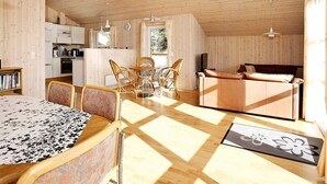 A spacious room with a wooden ceiling, a dining area with wicker chairs, a sofa, and a kitchen area with white cabinets. - 8 Person Holiday Home in Thisted-by Traum (Thisted)