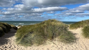 A sandy beach with dunes and a clear view of the ocean under a partly cloudy sky. - 8 Person Holiday Home in Thisted-by Traum (Thisted)