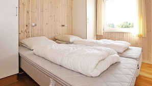 A bedroom with two single beds, wooden walls, a window with curtains, and a wardrobe. - 8 Person Holiday Home in Thisted-by Traum (Thisted)