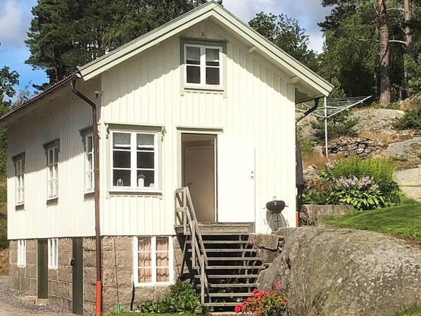 A two-story building with a white exterior, a front door, and a staircase leading to the entrance. - 5 Person Holiday Home in Kungshamn (Kungshamn)