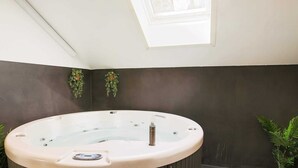 A hot tub in a room with a skylight, dark walls, and potted plants. - Wooden Holiday Home in Falster near Sea (Vaeggerlose)