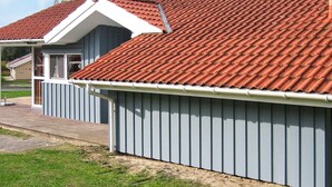 A residential building with a red-tiled roof, a grey siding exterior, and a visible chimney. - Holiday Home in Otterndorf (Otterndorf)