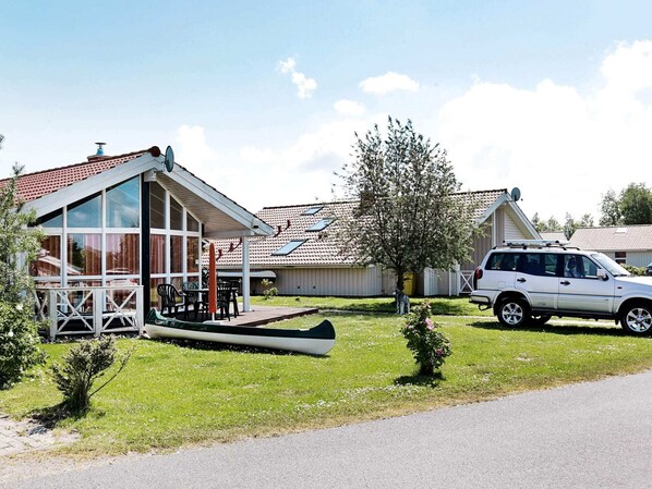 A building with large windows, a covered patio, and a parked car.