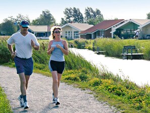 Zwei Personen joggen auf einem Weg, im Hintergrund Häuser.