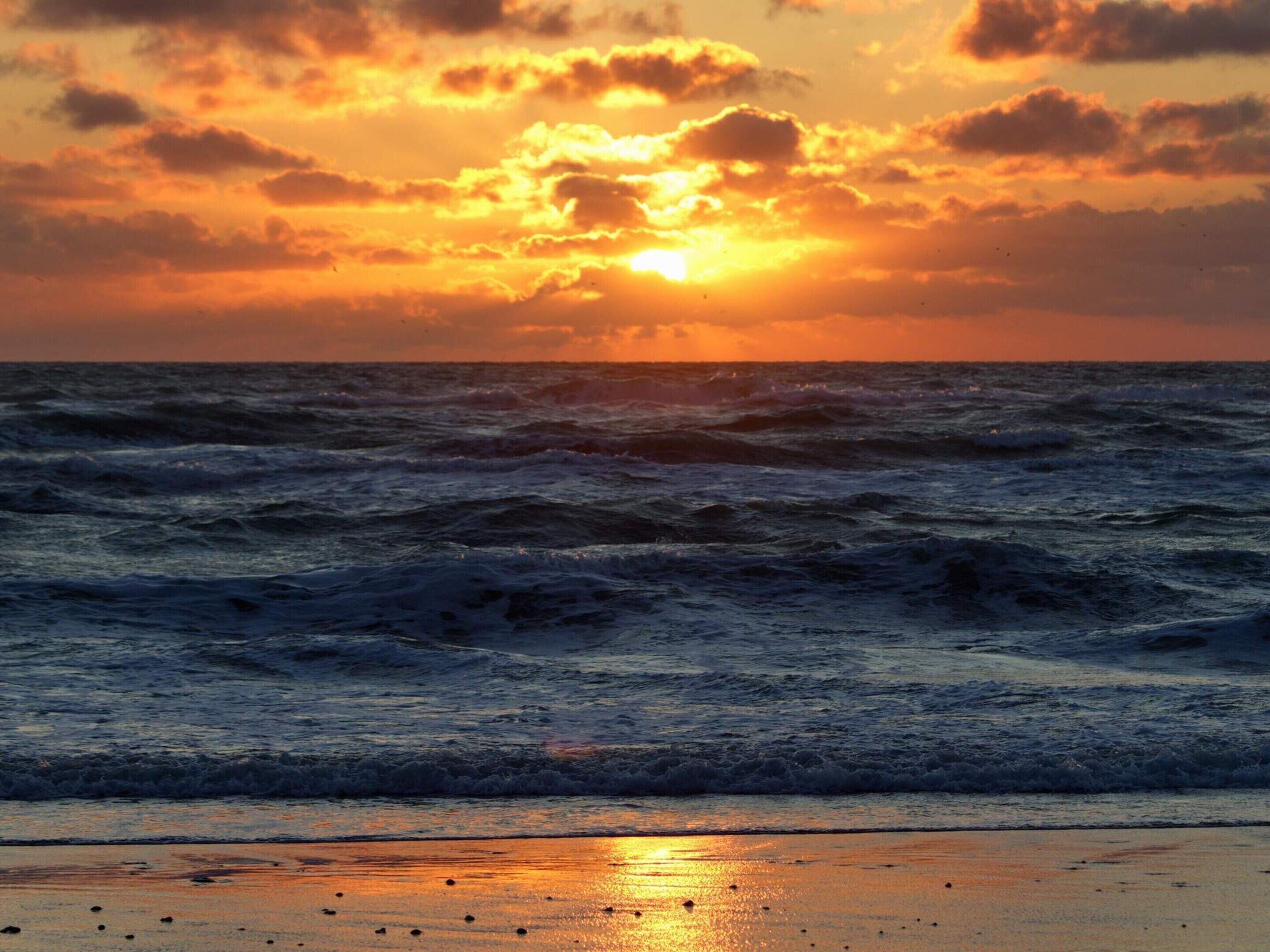 A sunset over the ocean with waves.