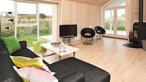 Una sala de estar moderna con un televisor grande, dos sillones negros, un sofá y una chimenea.