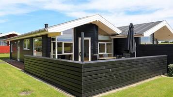 A modern house with a covered patio, large windows, and a black exterior.